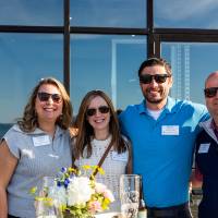 Group of 4 standing outside, smiling at camera with sunglasses on